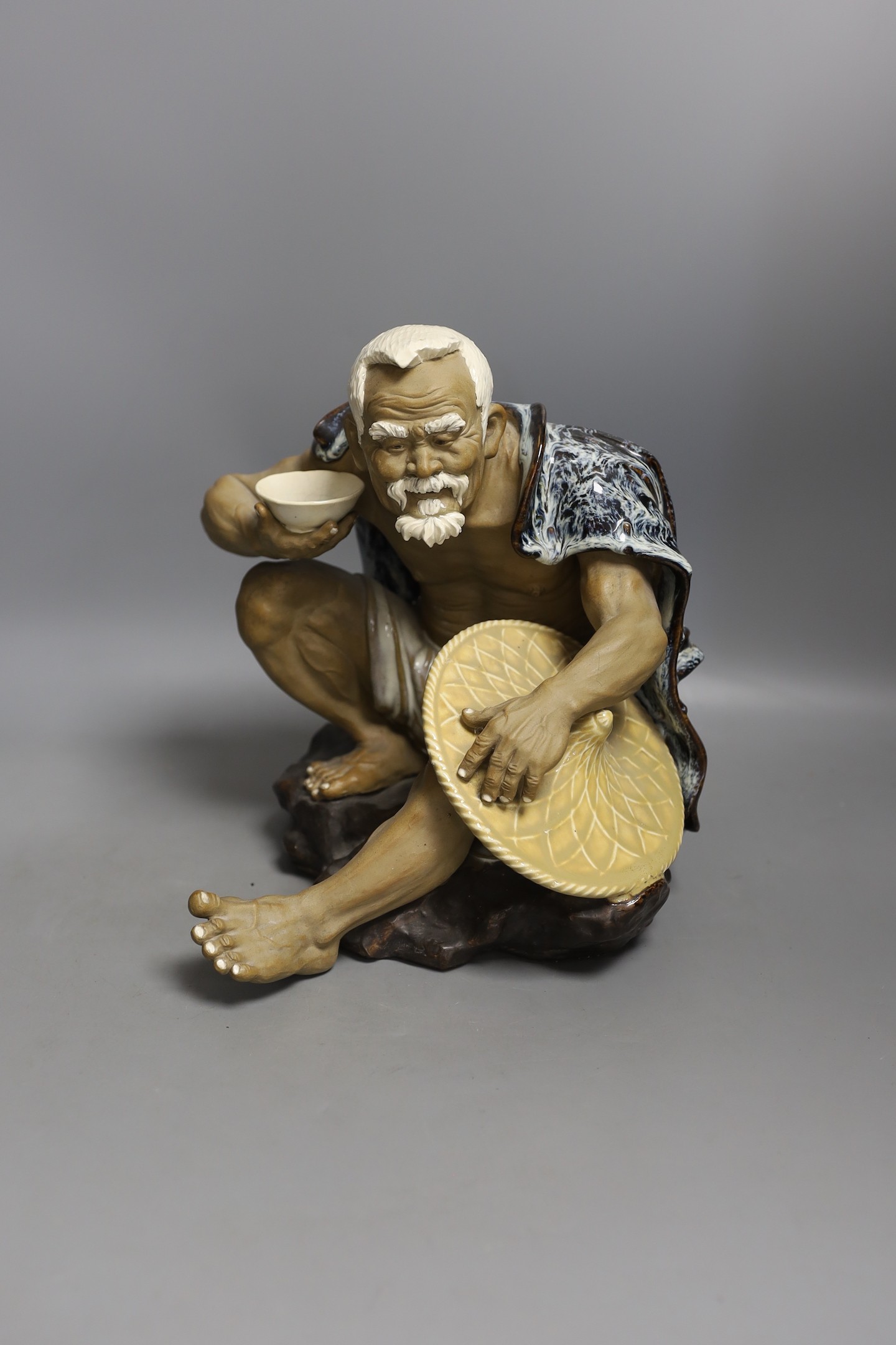 A large Chinese Shiwan pottery figure of seated monk, 25cm